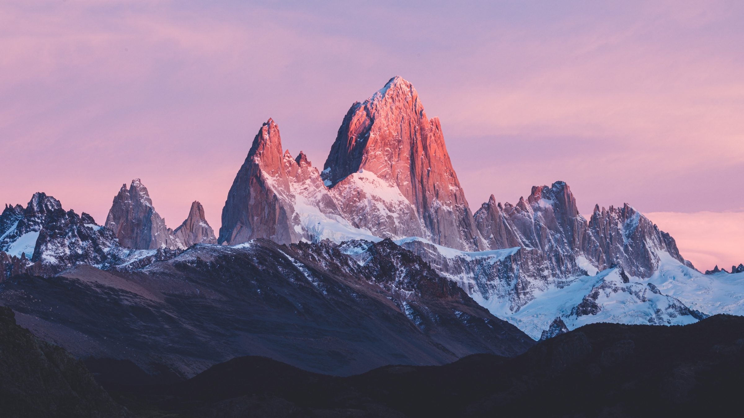 Mount Fitz Roy peaks glowing pink at sunrise above Patagonian foothills