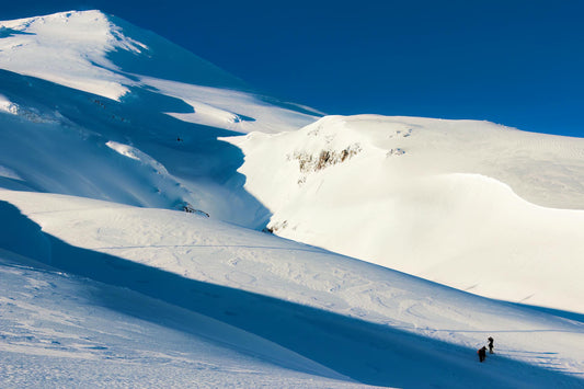 Skiers ascending the snow-covered cone of Villarrica volcano near Pucon, Chile, in low-angle light