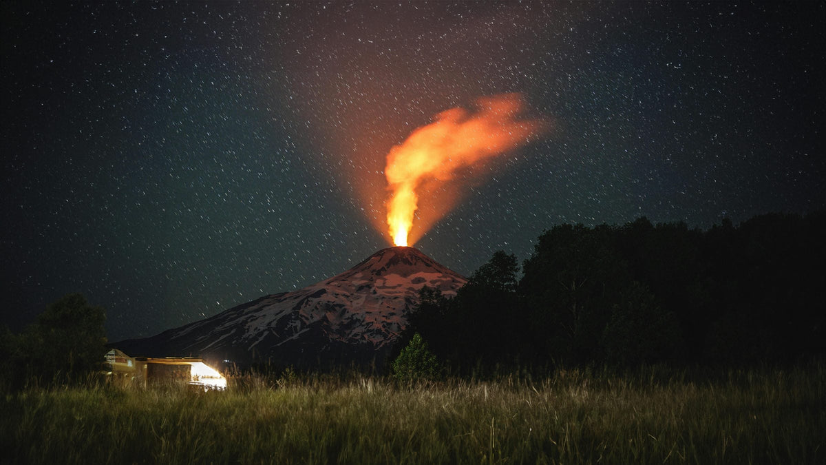 Villarrica volcano erupting at night with glowing lava plume over snow and stars, Chilean Andes
